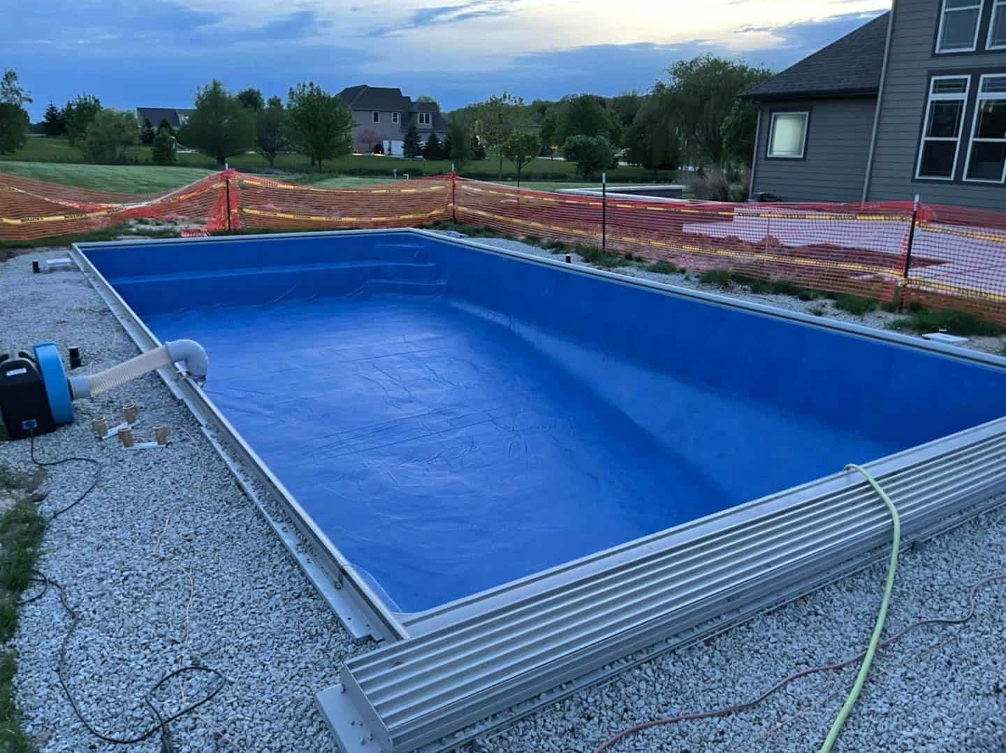 A blue swimming pool being installed in a backyard.