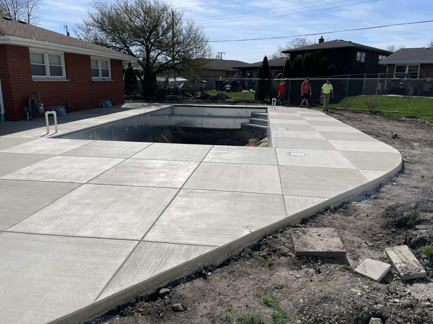 A concrete pool is being built in a backyard.