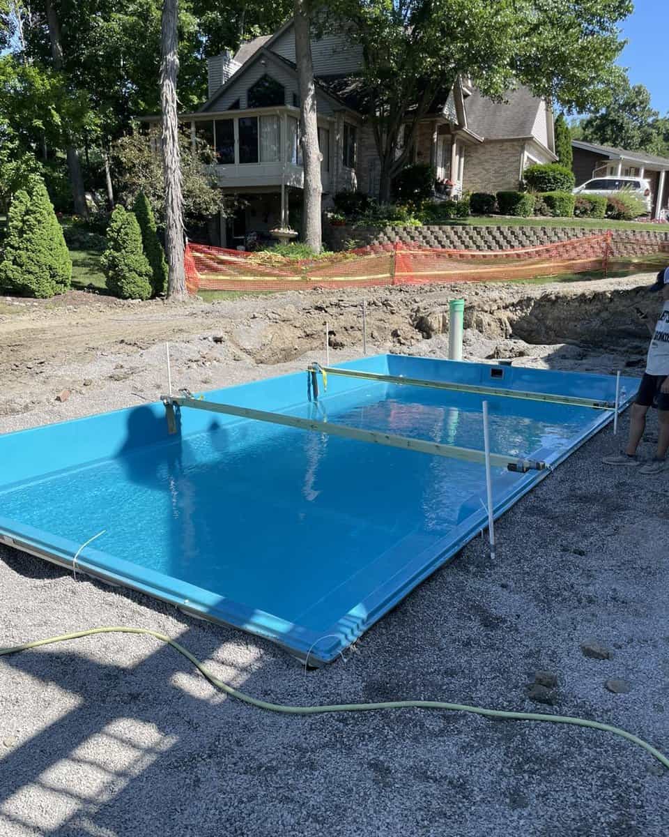 A man is installing a pool in a backyard.