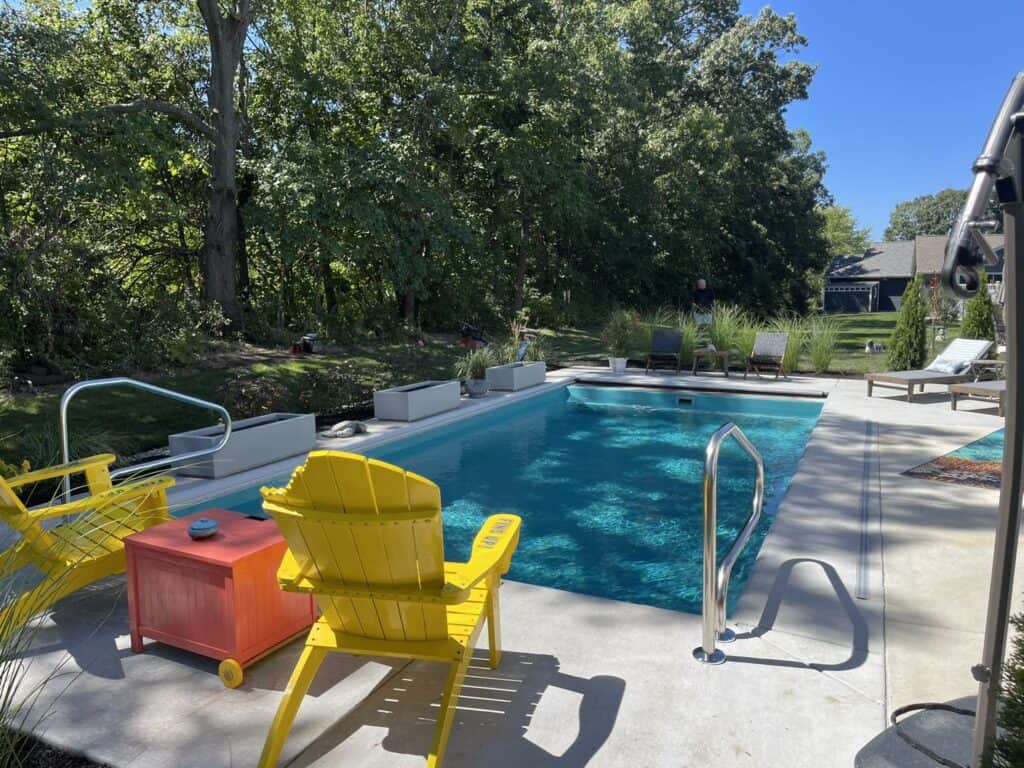 A backyard with a pool and chairs.