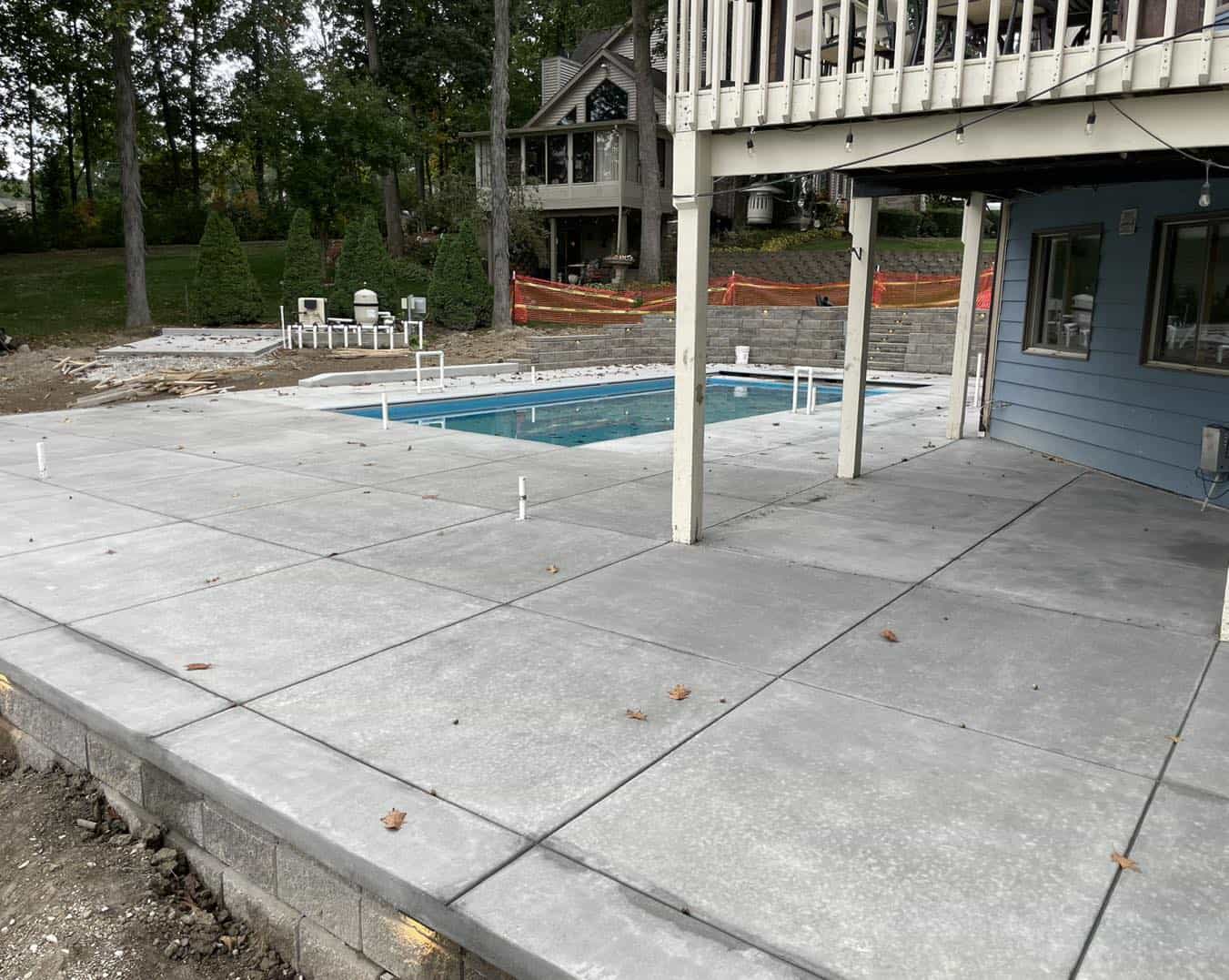 A concrete patio with a pool in the background.