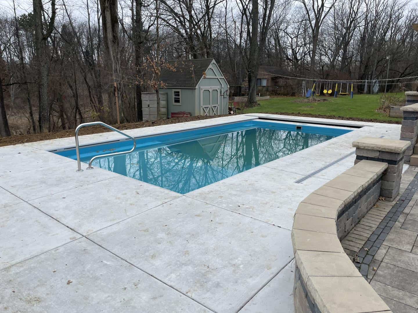 A swimming pool in a backyard with a deck.
